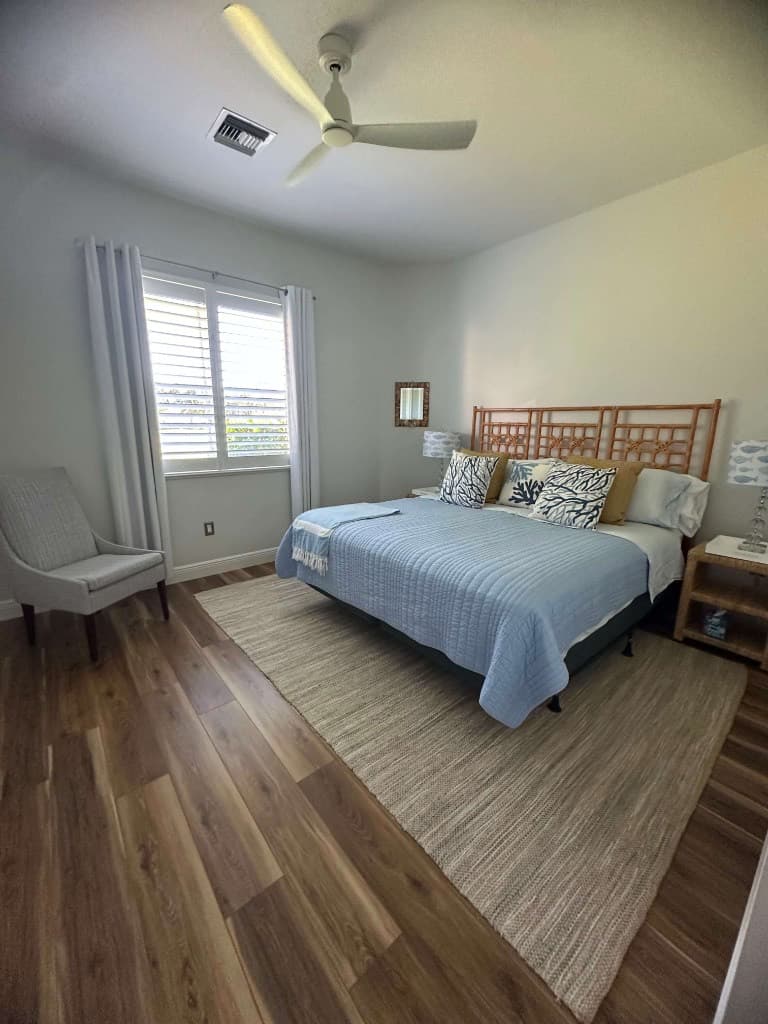 Bright coastal bedroom with neatly made bed and organized furnishings